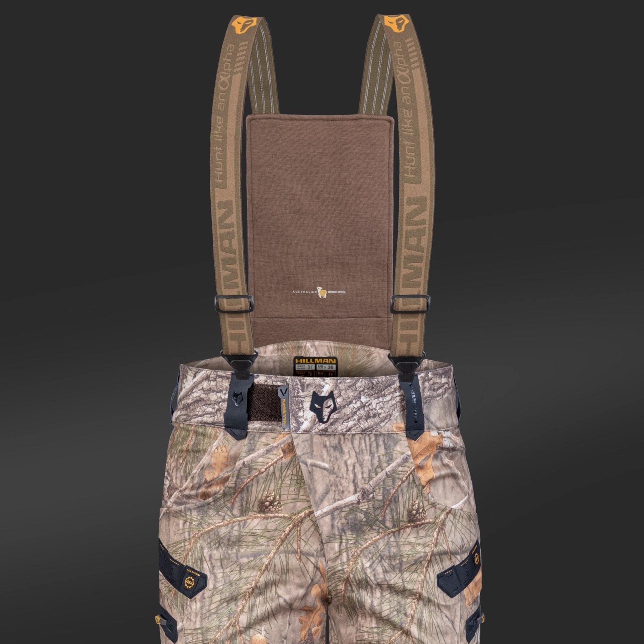 Set against a dark background, the HILLMAN GEAR 6OL Matrix Insulated Hunting Trousers feature tree and foliage camo patterns, multiple pockets, and branded suspenders. Designed for extreme cold, these waterproof bibs provide ultimate protection.