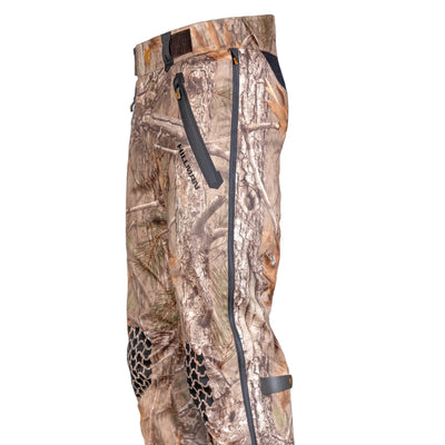 The 5WL Ultra-Lightweight Waterproof Hunting Trousers by HILLMAN GEAR feature a natural woodland pattern, zippered pockets, and durable textured knee pads. These breathable pants have belt loops, a reinforced side seam, and seamlessly blend into forest environments.