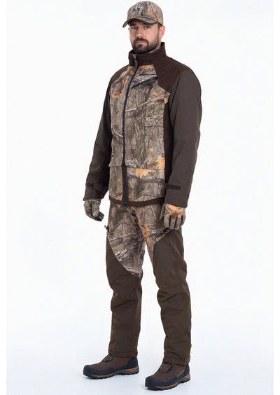 A man faces forward in fusion waterproof hunting trousers, a camouflage jacket, brown boots, and a camo cap, set against a plain white background.