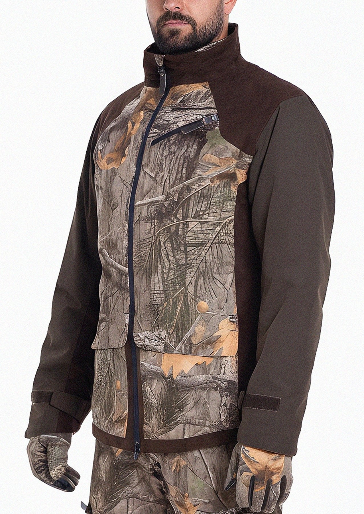 A man wears the Hillman® Fusion Hunting Jacket 3DX with dark brown sleeves and panels, matching camouflage gloves, and pants. The breathable jacket features a zip front and high collar. His face is partially visible against a white background.