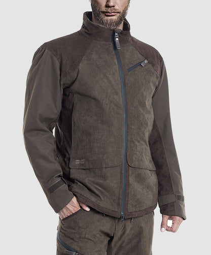 A man wears the Hillman® PRE ORDER Fusion Hunting Jacket—a brown, waterproof outdoor jacket with a high collar and zippered chest pocket—paired with matching brown pants, standing against a plain light gray background.