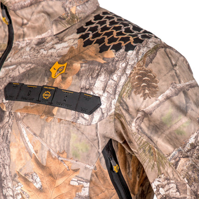 Close-up of HILLMAN GEAR’s ultra-lightweight camo rain jacket, a waterproof camouflage hunting coat with tree branches, leaves, and pinecones. Features a yellow fox logo, black accents, and a zippered rectangular chest patch with slots.