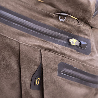 Close-up of a brown suede jacket with black waterproof zippers and gold accents, showcasing detailed stitching. Perfectly pairs with HILLMAN GEAR Waterproof Bibs insulated hunting trousers for reliable outdoor performance.