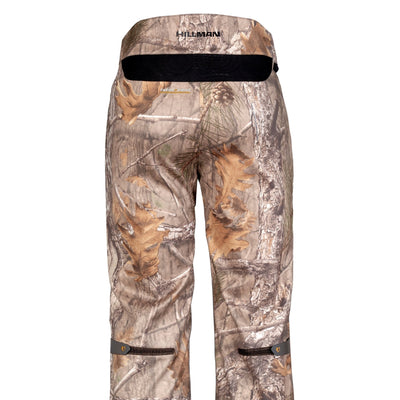 The 5WL Ultra-Lightweight Waterproof Hunting Trousers by HILLMAN GEAR feature a woodland pattern with leaves and branches. These breathable pants include buttoned pockets at the rear and near the knees, displaying HILLMAN on the waistband.