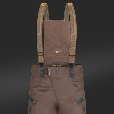 The 6OL Matrix Insulated Hunting Trousers by HILLMAN GEAR are waterproof bibs on a black background, designed for extreme cold. They feature olive green suspenders with orange clips and brand logo, black reinforced patches, and multiple pockets.
