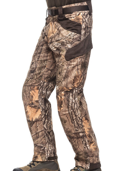 A person wearing Hillman® XPR Silent Hunting Trousers in a tree and leaf camo pattern with brown accents, paired with brown boots and a visible belt.